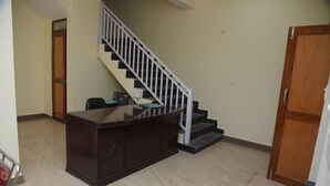 A room with a wooden desk, a staircase with white railings, and a wooden door. - Hotel Lake Paradise Inn (Nainital)