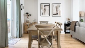 Un coin repas avec une table et des chaises en bois, un vase rempli de fleurs et deux tableaux abstraits accrochés au mur.