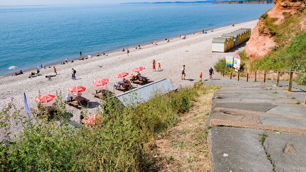 Une plage avec des parasols et des gens.