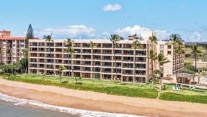 A beachfront hotel with multiple floors, a pool area, and palm trees.