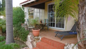 Eine Terrasse mit einem Stuhl, einem Tisch und einem Blumentopf.