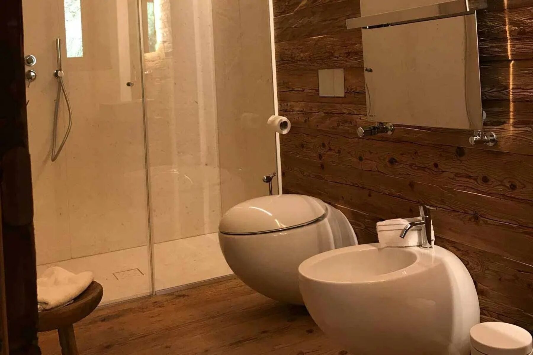 Une salle de bain avec un mur en bois, une douche, des toilettes et un lavabo.