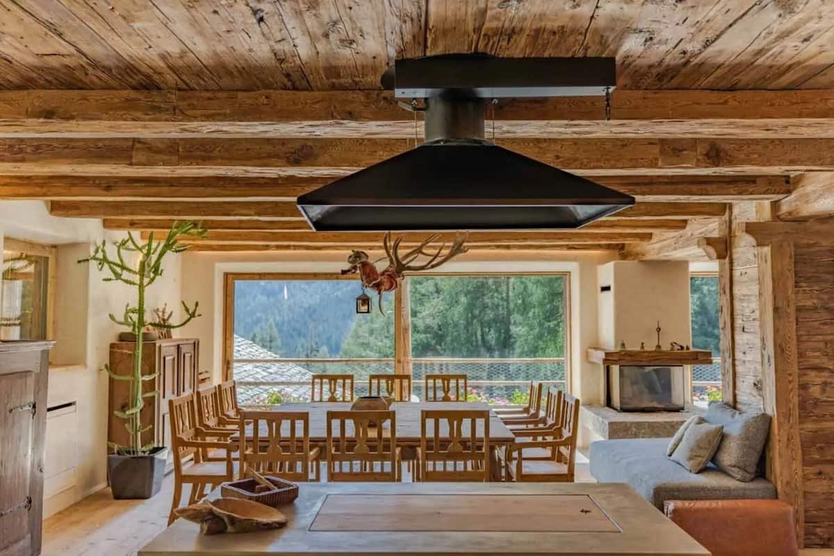 Un interior rústico de madera con comedor, sofá y chimenea.