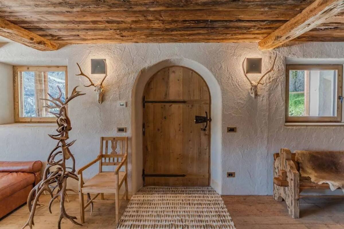 Un interior rústico con una puerta de madera, un banco y adornos de asta.