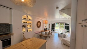 Una cocina moderna con encimera de madera, un comedor con mesa y sillas, y un dormitorio con cama y ventana.