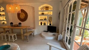 Un amplio salón con una mesa de comedor de madera, sofás blancos y un ventanal con vistas al exterior.