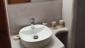Ett badrum med ett vitt handfat, en spegel, en handdukshängare och en tvålpump.