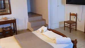 Ett hotellrum med en säng, ett skrivbord med en stol, en tv och en trappa som leder till ett annat rum.