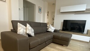 Un salon moderne avec un canapé d’angle marron, un téléviseur à écran plat et une cheminée.