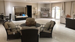 Ein geräumiges Wohnzimmer mit einem runden Couchtisch, zwei Sesseln, einer Couch und einem Stockbett mit floralem Baldachin.
