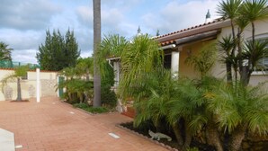 A paved pathway leading to a building with a tiled roof and a stone wall. - Bungalow with apartment in a quiet location and large pool (Burgau)