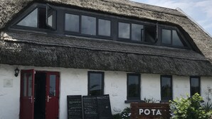 A building with a thatched roof, a red door, and a sign reading "POTA".