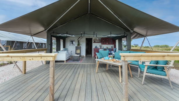 A covered outdoor area with a wooden deck, a sofa, and a table.
