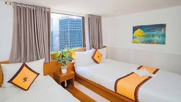 A hotel room with two beds, a nightstand with a plant, and a painting on the wall.