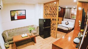 Un ambiente compatto con divano, tavolino, televisione e angolo cottura.