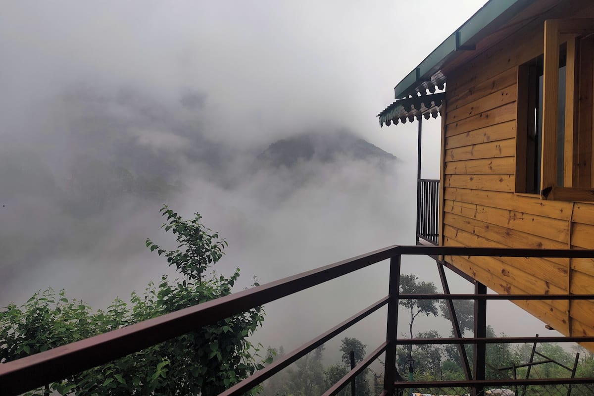 Ein hölzernes Gebäude mit Balkon, umgeben von Nebel und Grün.