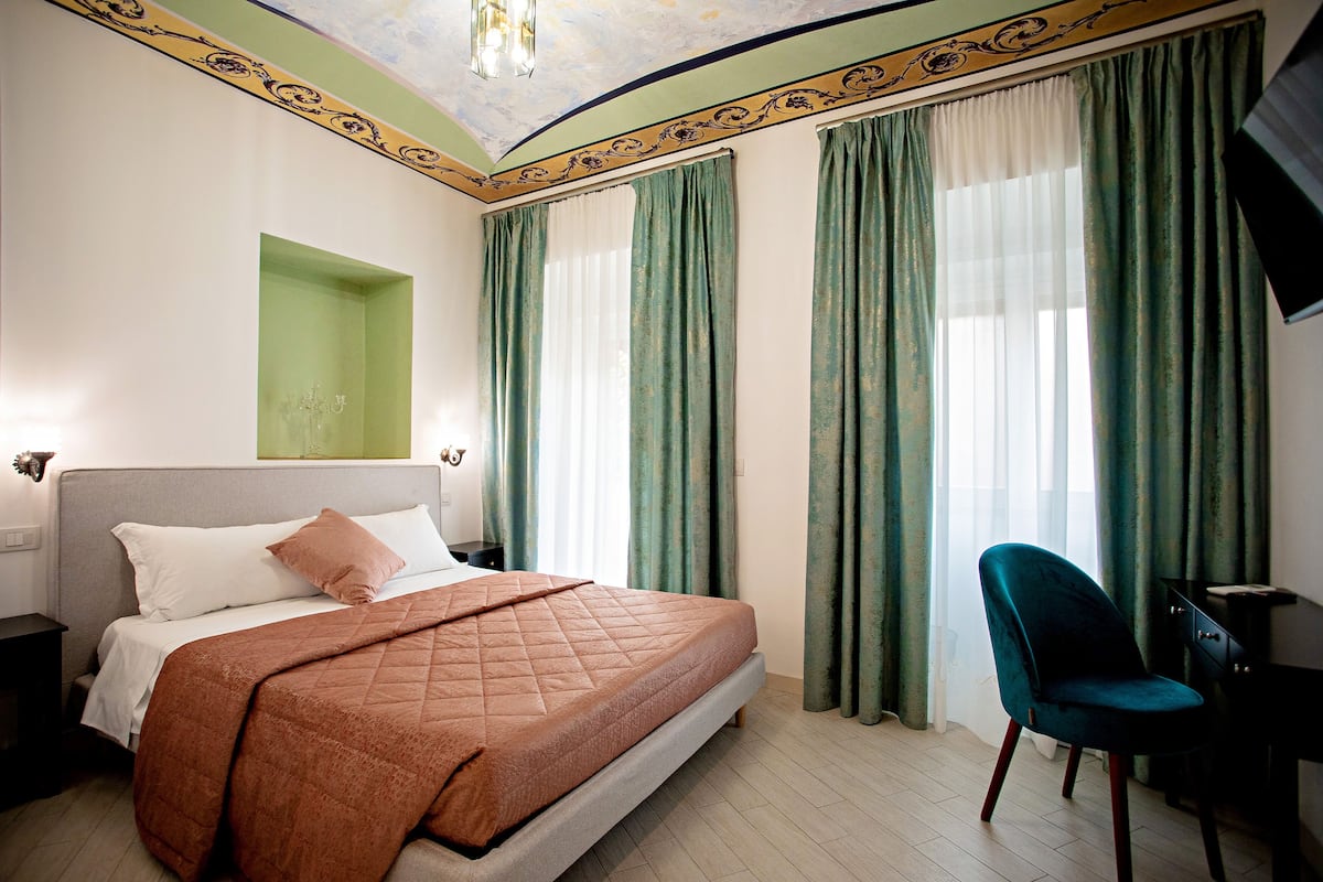 A bedroom with a bed, a nightstand, a chair, and a desk.