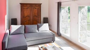 Ein modernes Wohnzimmer mit einem grauen Ecksofa, einem Holzschrank und einem bunten Couchtisch.