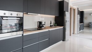 A modern kitchen with dark cabinetry, a stainless steel oven, a coffee machine, and a refrigerator. - Liberty's Canvas - Balcony Suite near Acropolis (Αθήνα)