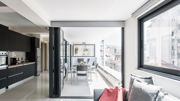 A modern apartment with a kitchen, dining area, and a balcony with a view of the city. - Liberty's Canvas - Balcony Suite near Acropolis (Αθήνα)