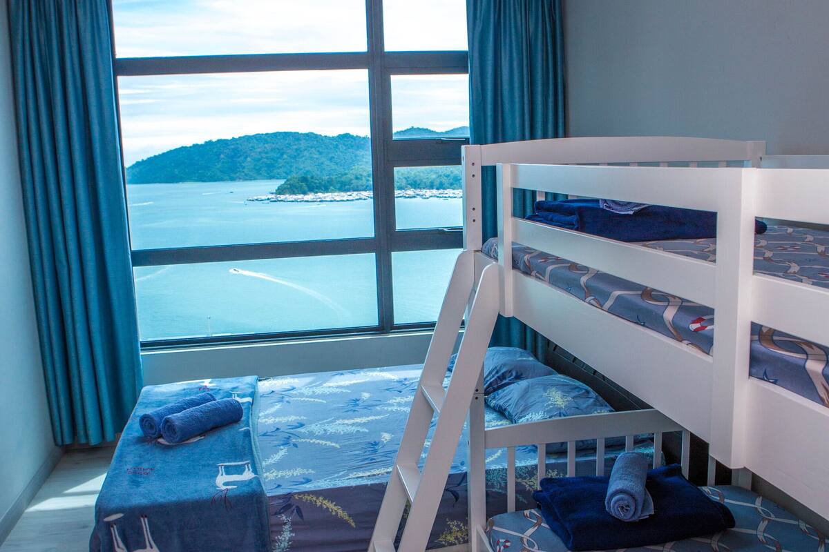A bunk bed room with a large window, a view of the sea, and an air conditioning unit.