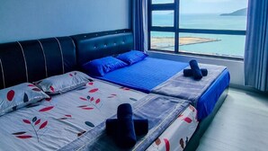 A hotel room with two beds, a large window with a view of the sea, and a blue bedspread. - Jesselton Point Homestay  (Kota Kinabalu)