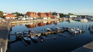 Satamassa on laivoja, rakennuksissa on punaiset katot ja taivas on kirkas.