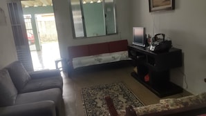 A living room with a sofa, a TV, and a small table. - Simple and spacious house for Carnival. (Mongaguá)