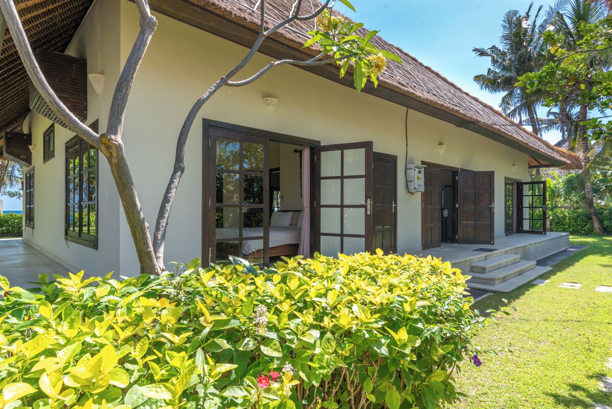 A two-story building with a thatched roof, large windows, and a covered porch.