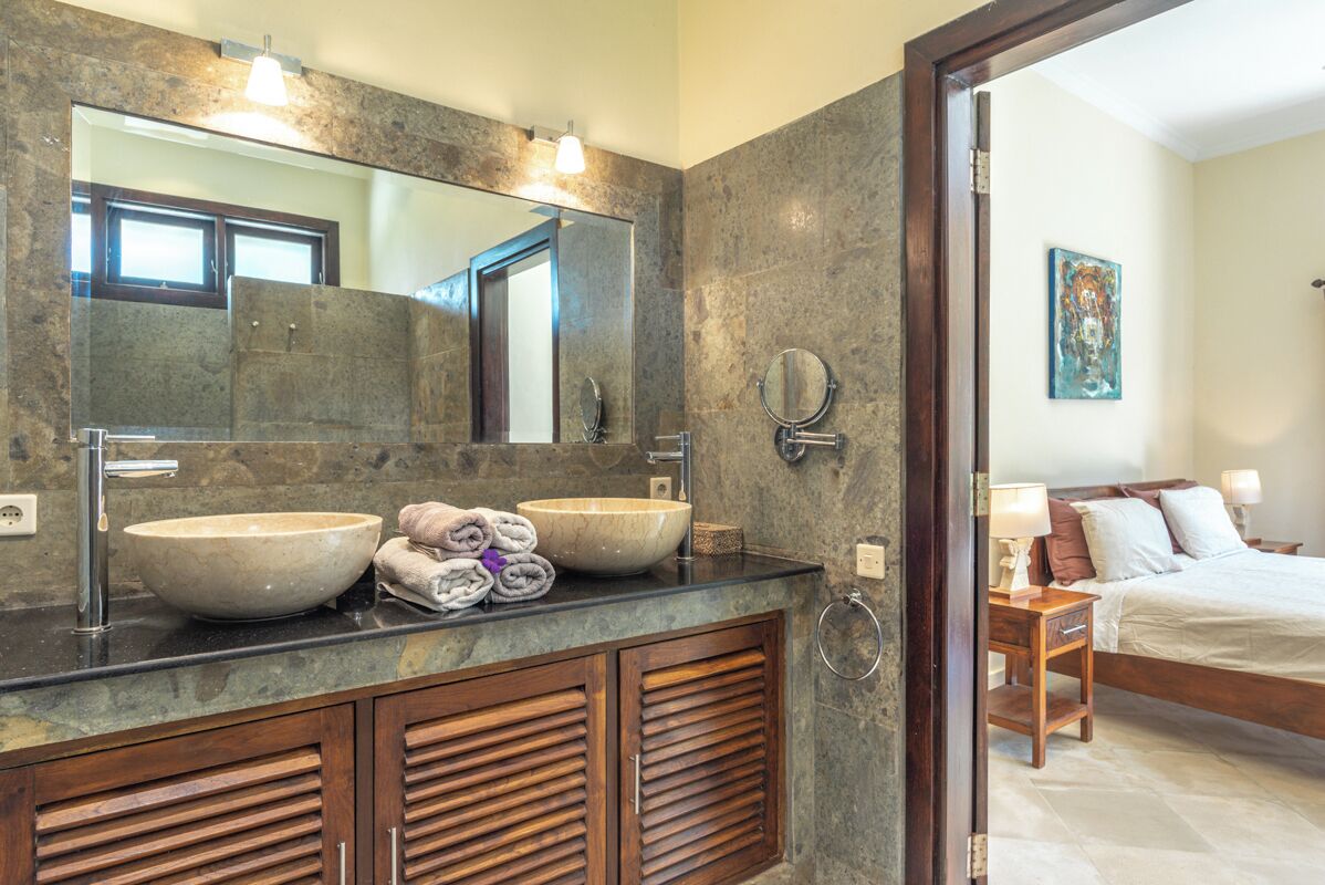 Une salle de bain avec un grand miroir, deux lavabos et un meuble-lavabo en bois.