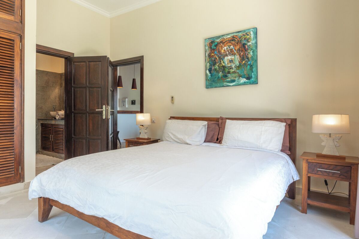 Ein Schlafzimmer mit einem großen Bett, einem Holzschrank und einem Bild an der Wand.