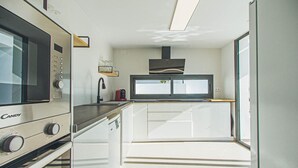 Een kleine keuken met een magnetron, een koffiezetapparaat en een raam boven de gootsteen.