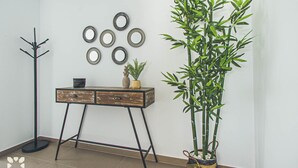 Een kamer met een houten consoletafel, een hoge bamboeplant en decoratieve wandborden.