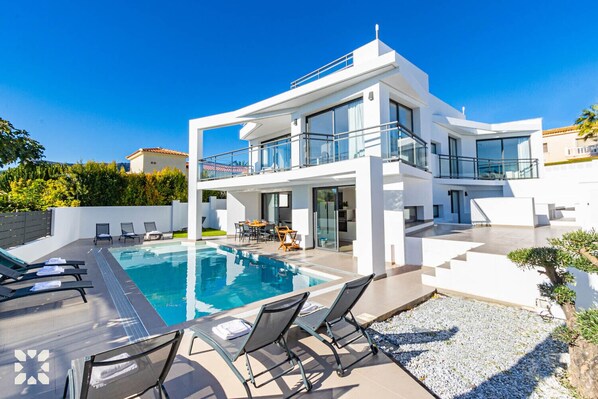Une maison moderne à deux étages, dotée d’une piscine, d’un espace extérieur aménagé et d’un jardin bien entretenu.