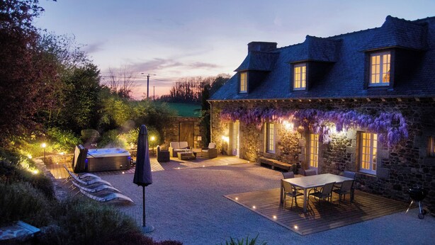 Une maison en pierre dotée d’un patio aménagé avec des meubles d’extérieur et un jacuzzi.