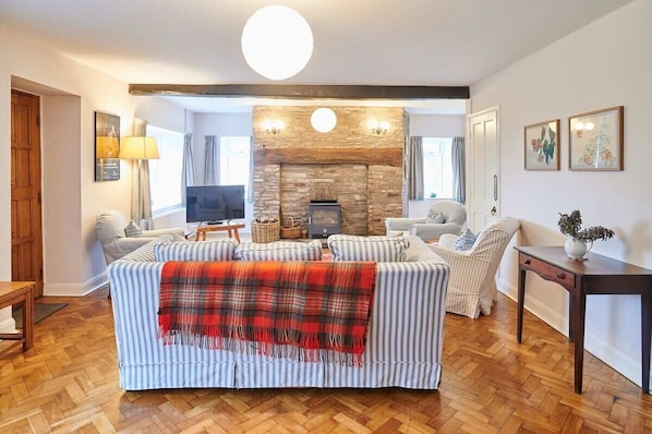 A living room with a fireplace, a sofa, a TV, and a wooden floor.