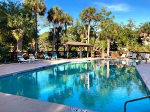 A swimming pool with lounge chairs and a gazebo surrounded by palm trees. - 203 Deer Run - Private Sauna, Neighborhood Pool, Full Resort Access Available! (Saint Helena Island)