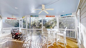 Un espace extérieur abrité doté d’une terrasse en bois, de rampes blanches et de panneaux indiquant les options de fruits de mer, comme « homard vivant », « mahi-mahi frais », « vivaneau rouge » et « beignets de crabe ».