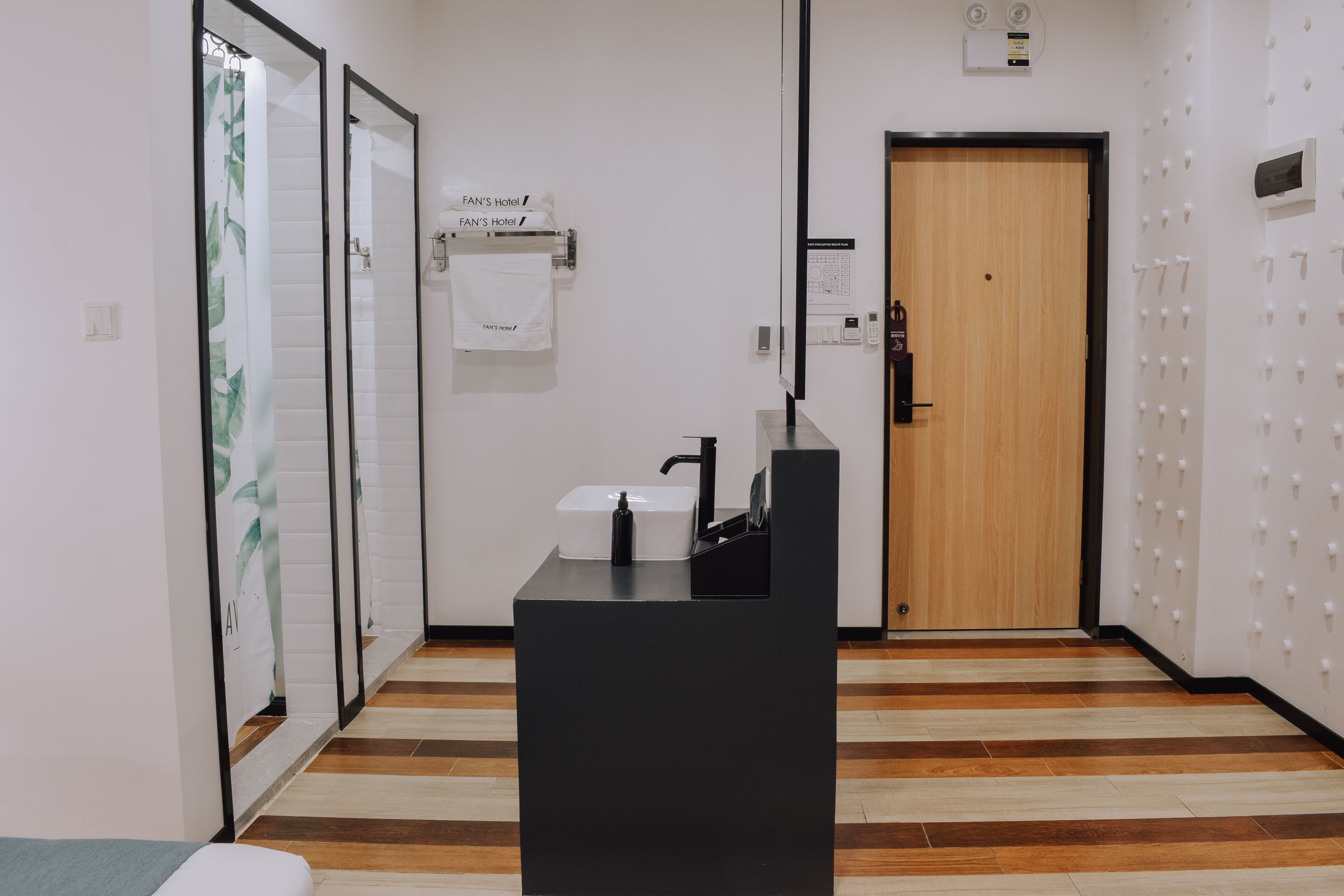 Un espace d’accueil d’hôtel avec un comptoir noir, une porte en bois et un distributeur de serviettes fixé au mur.