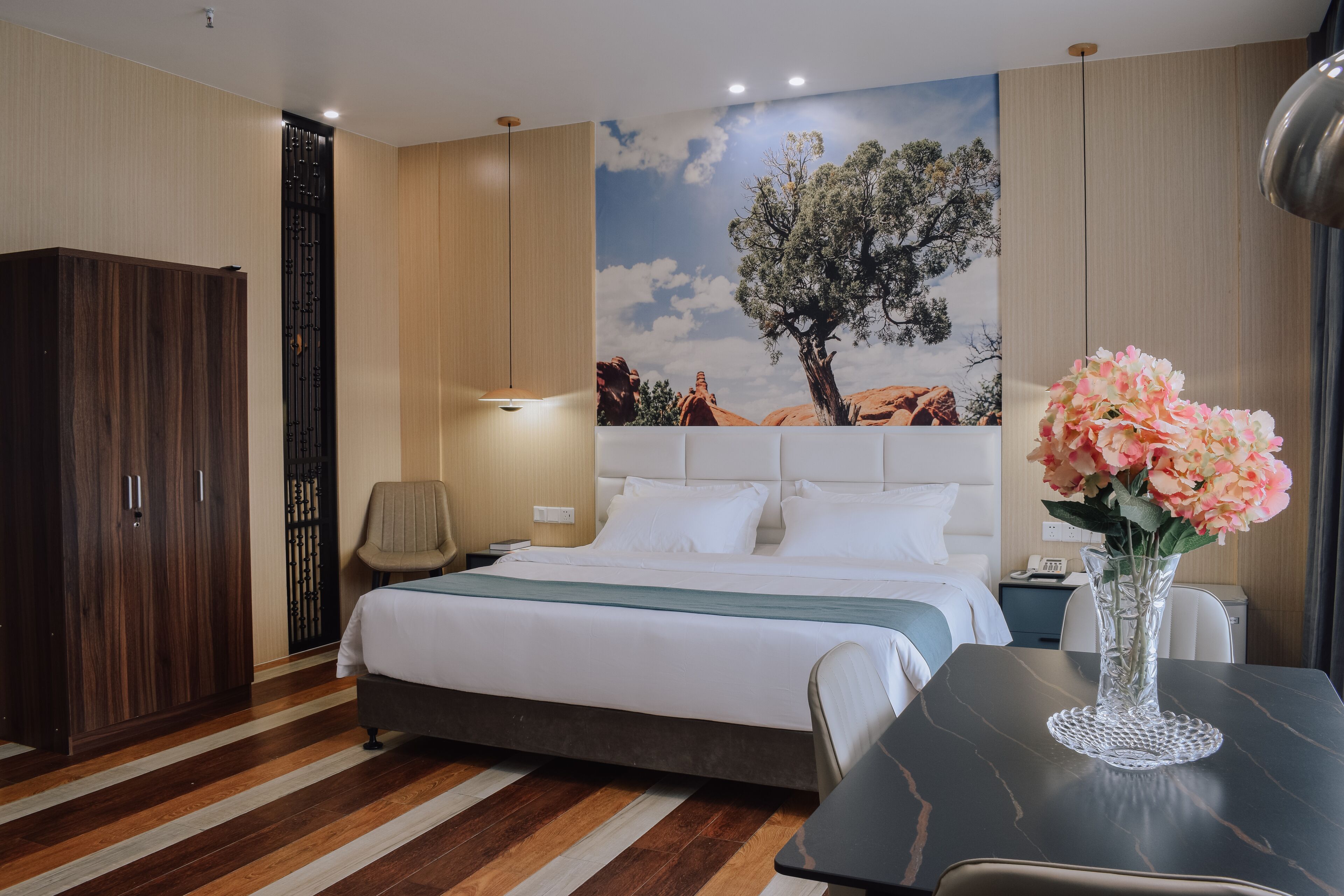 Une chambre d’hôtel comprenant un lit, un bureau, une chaise, une armoire et une décoration murale.
