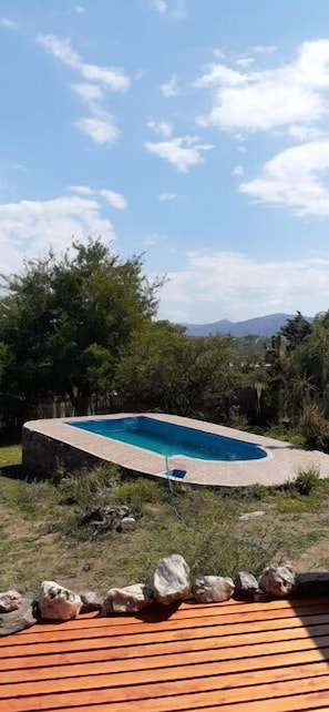 Piscina rodeada por paisagem natural e um deck de madeira.