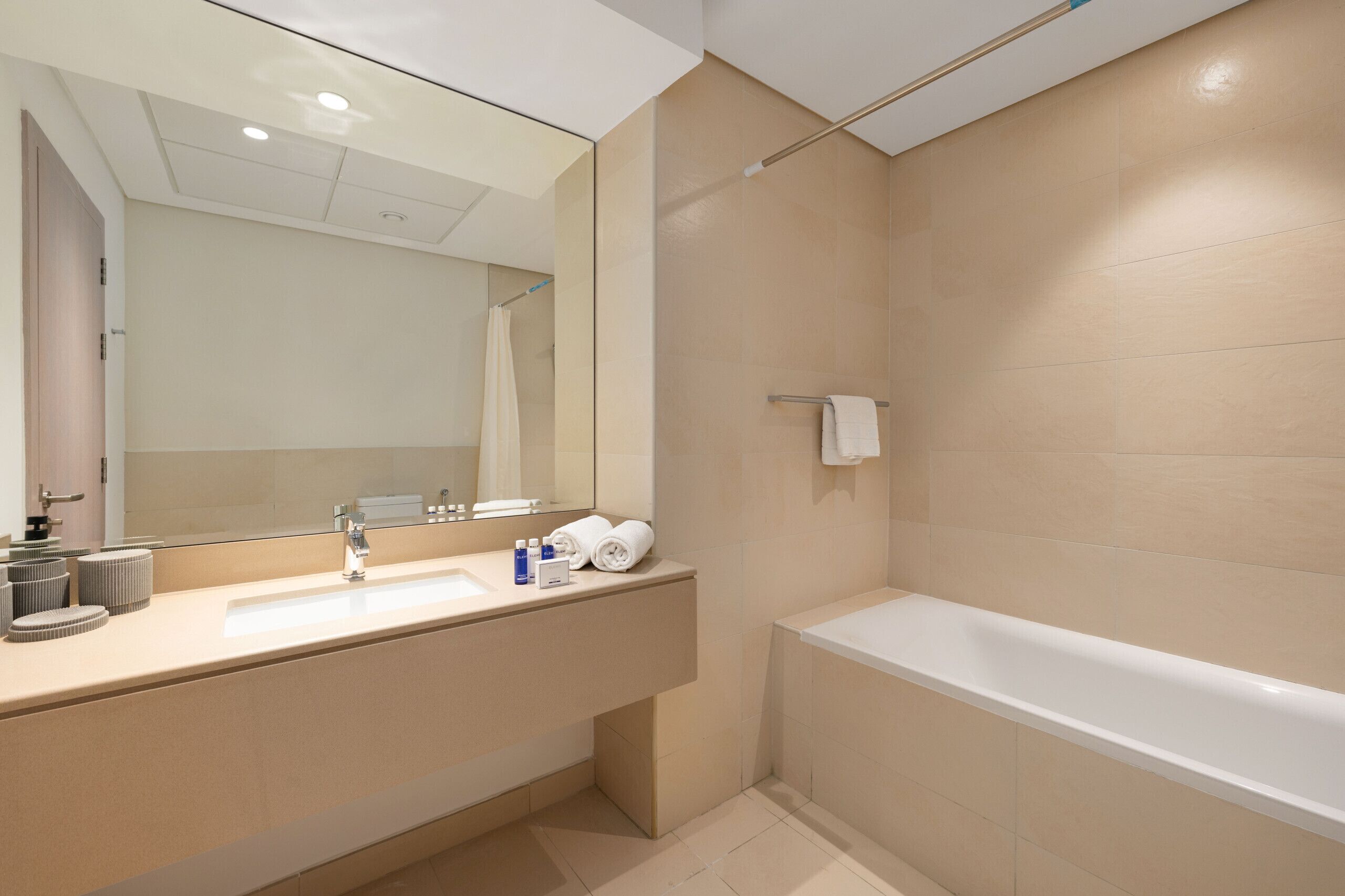 Un bagno moderno con uno specchio grande, un lavandino e una vasca da bagno.