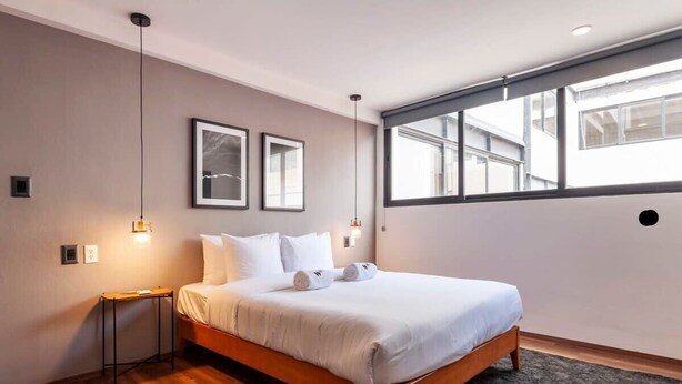 Ein modernes Schlafzimmer mit einem Holzbett, zwei Nachttischen und einem großen Fenster, das für natürliches Licht sorgt.