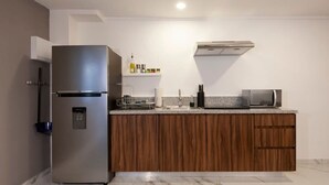 Eine moderne Küche mit Einbaukühlschrank, Holzschränken, einer Mikrowelle und einem Wasserspender.