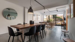 Un comedor moderno con una larga mesa de madera, sillas negras y un espejo redondo en la pared.