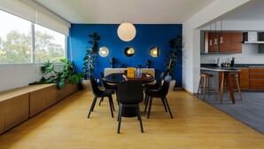 A modern dining area with a round table, black chairs, and a blue accent wall. - w* | Polished 3BR Duplex in Condesa (Ciudad de México)