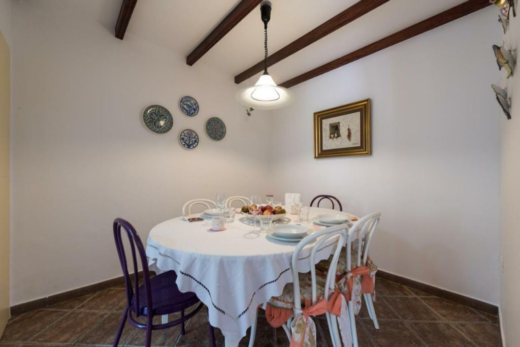 A dining area with a round table set for four, white chairs, and a hanging light fixture.