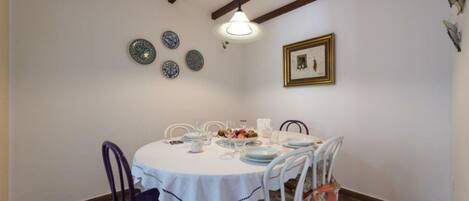 A dining area with a round table set for four, white chairs, and a hanging light fixture.