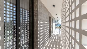 Um corredor com piso e paredes estampados, que leva a uma área externa iluminada.