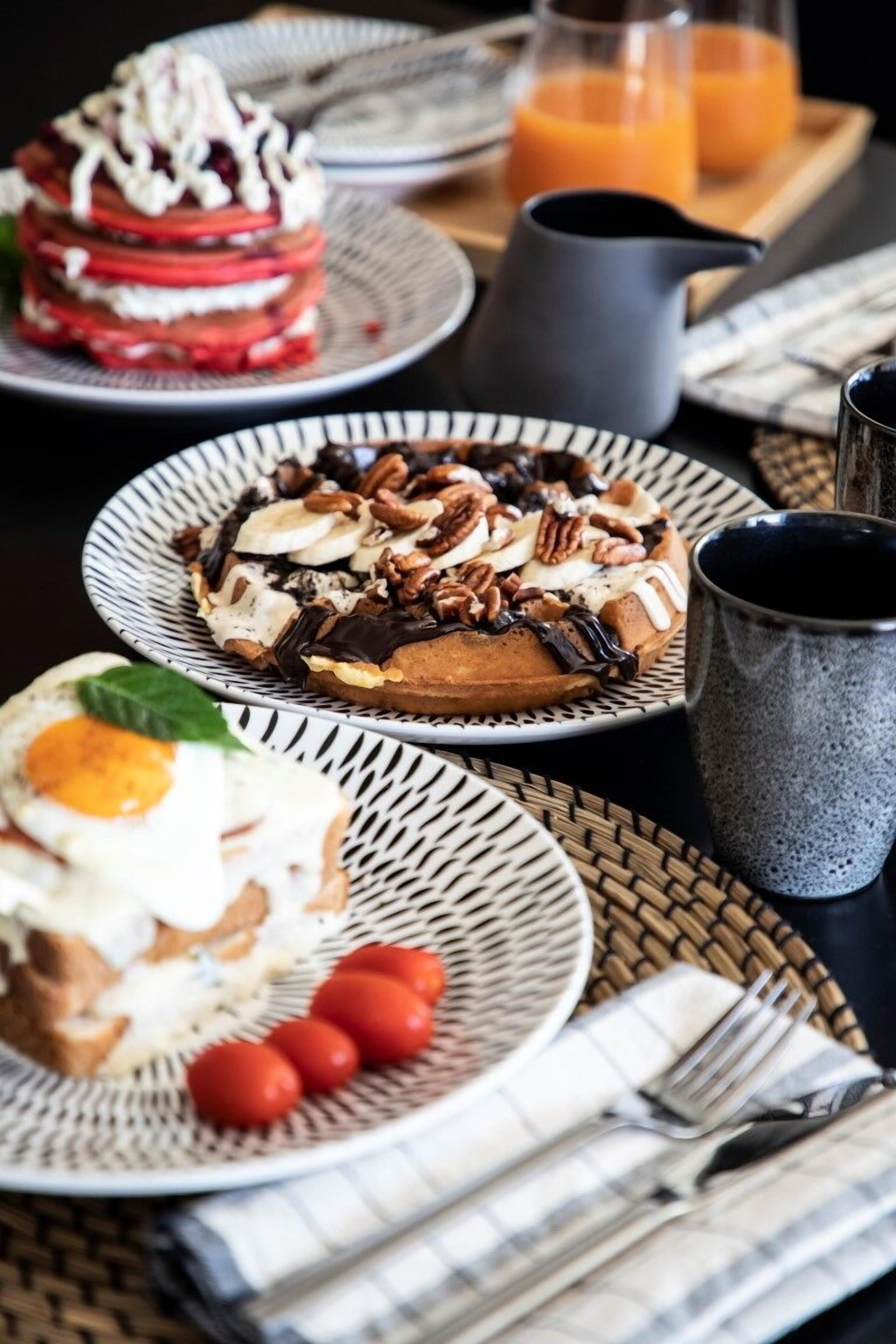 Mesa de café da manhã com pratos de comida, um jarro e uma caneca.